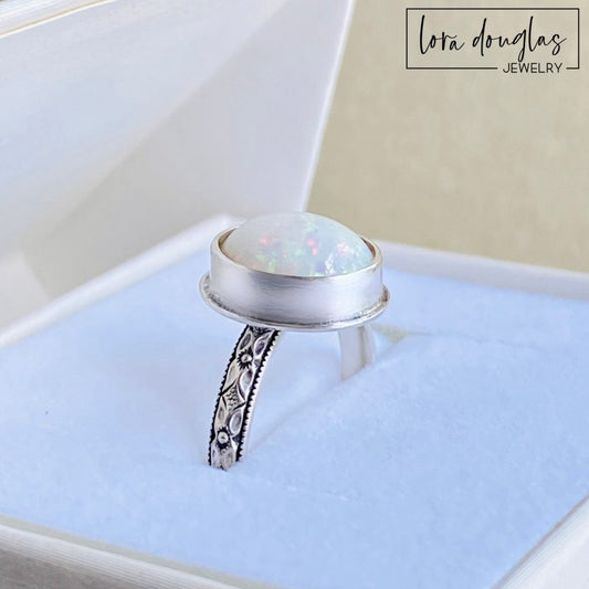 Sterling silver opal ring featuring a hand cut 10mm x 12mm cabochon in an oval bezel setting, handcrafted in finished US size 7.75 for lovers of natural opal jewelry and artisan silver rings.
