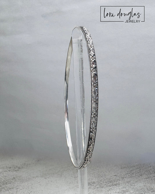 Artisan sterling silver bangle bracelet featuring detailed texture and high polish handmade design.