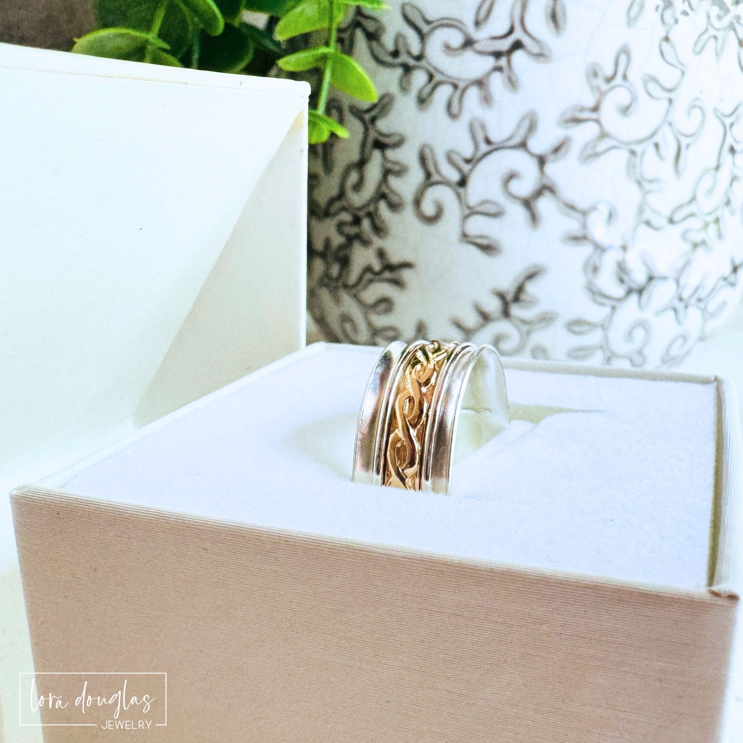 Close-up of handcrafted spinner ring showing polished sterling silver edges and gold-filled center band, jewelry by Lora Douglas.
