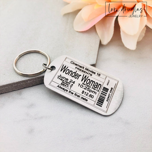 A stainless steel key chain featuring an engraved design of a movie ticket personalized with event info.