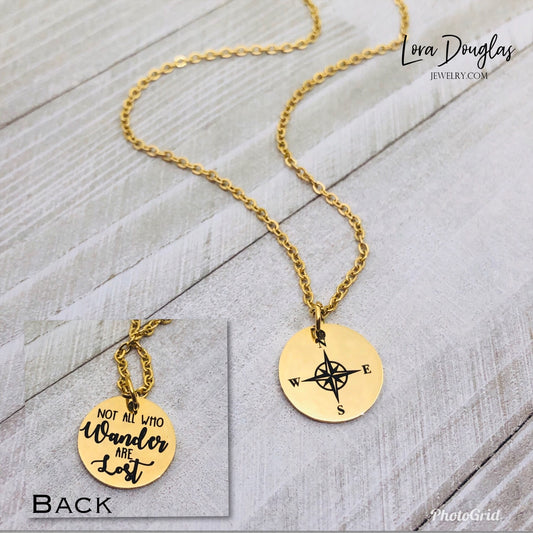 Gold stainless steel compass jewelry with a round pendant that reads 'Not all who wander are lost' on a chain.