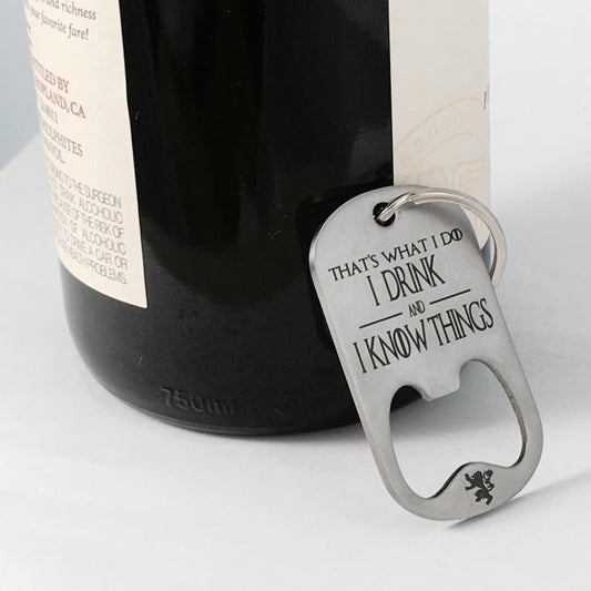 A stainless steel key chain with the engraved text 'That's What I Do I Drink and I Know Things' along with the HBO logo for Game of Thrones, resting on a corkscrew.
