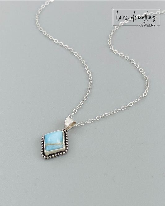 A sterling silver pendant necklace with a turquoise stone and a silver chain.