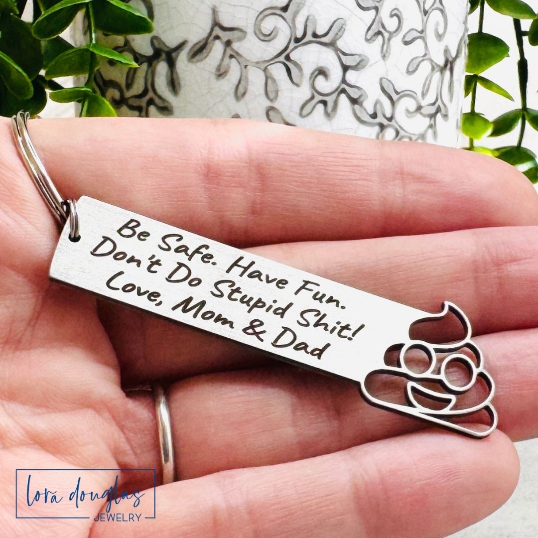 Keychain with engraved message held in a hand, with a decorative background.
Don't Do Stupid Shit Poop Emoji Cutout Keychain, Personalized Funny Stainless Steel Keyring, Customize With Your Name, Gift Bag Included