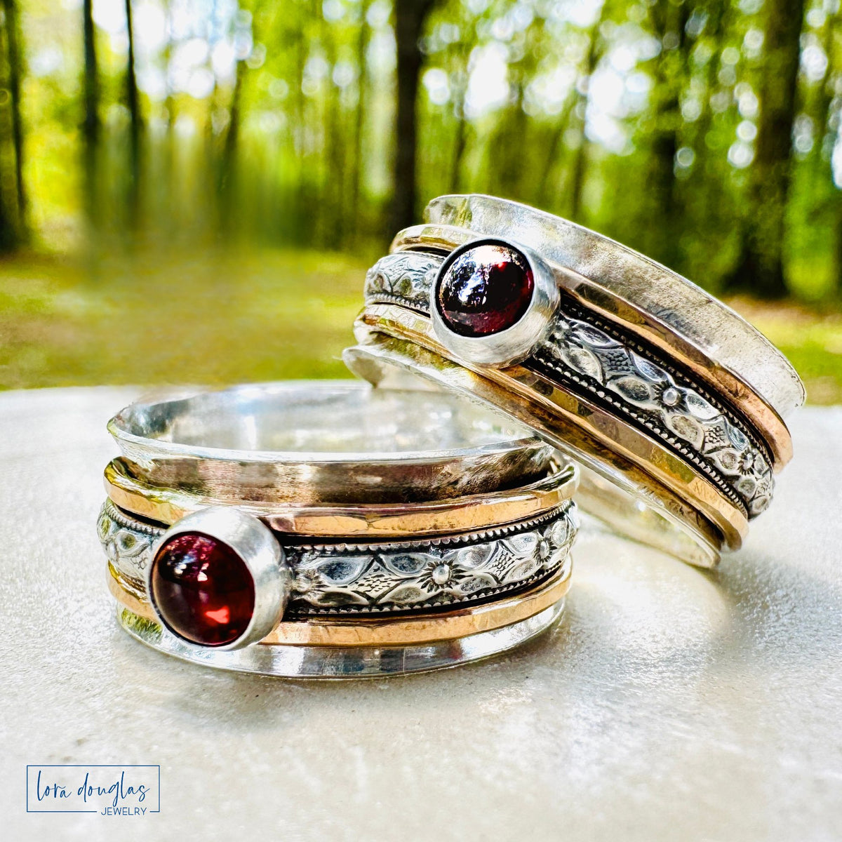 A bold, grounding piece with movement and texture. This handcrafted spinner ring features a wide sterling silver band layered with gold filled accents and a deep garnet stone that catches the light beautifully.