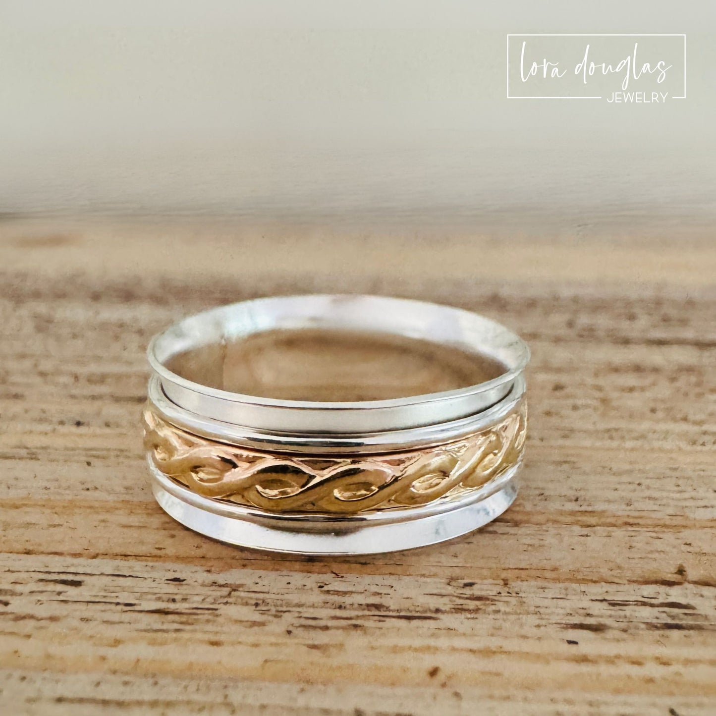 Artisan sterling silver and gold-filled spinner ring photographed at an angle to highlight the textured vine design and wide band.