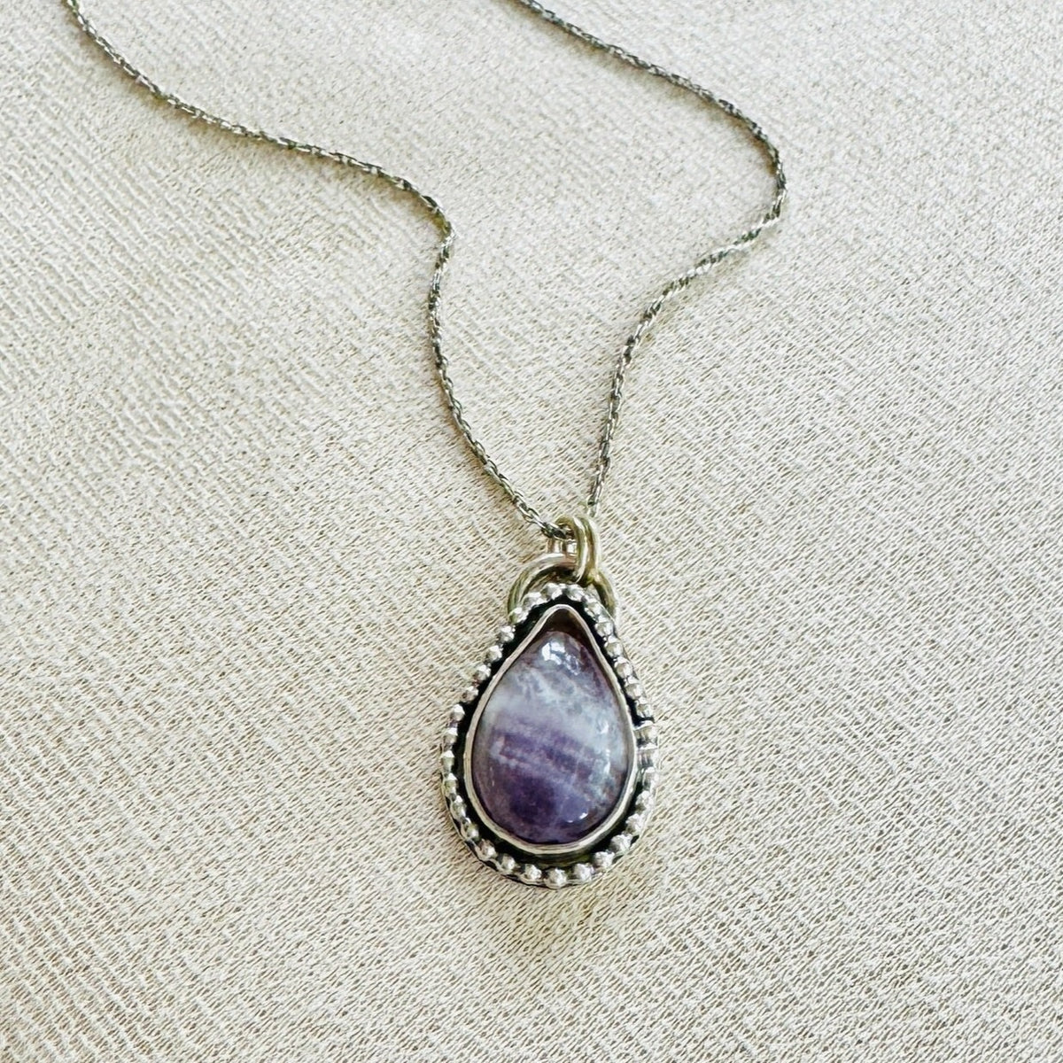 Banded amethyst sterling silver necklace featuring a natural purple gemstone in a teardrop pendant measuring approximately 17mm x 27mm, paired with an 18 inch silver chain for distinctive natural stone jewelry.
