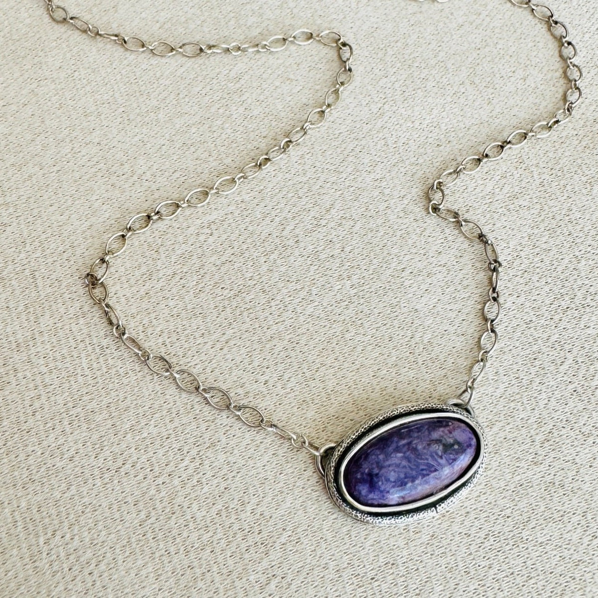 Charoite sterling silver necklace featuring a natural oval purple gemstone measuring approximately 23mm x 14.5mm on a silver chain, a distinctive choice for shoppers looking for natural stone jewelry.
