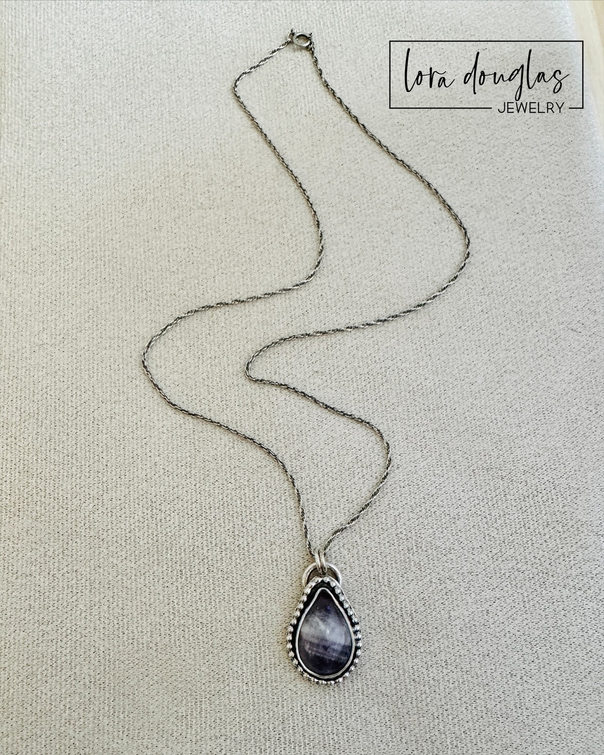 Close view of a banded amethyst teardrop pendant highlighting the natural purple shades and distinctive stone pattern, paired with sterling silver for a versatile necklace that lets the gemstone remain the focal point.
