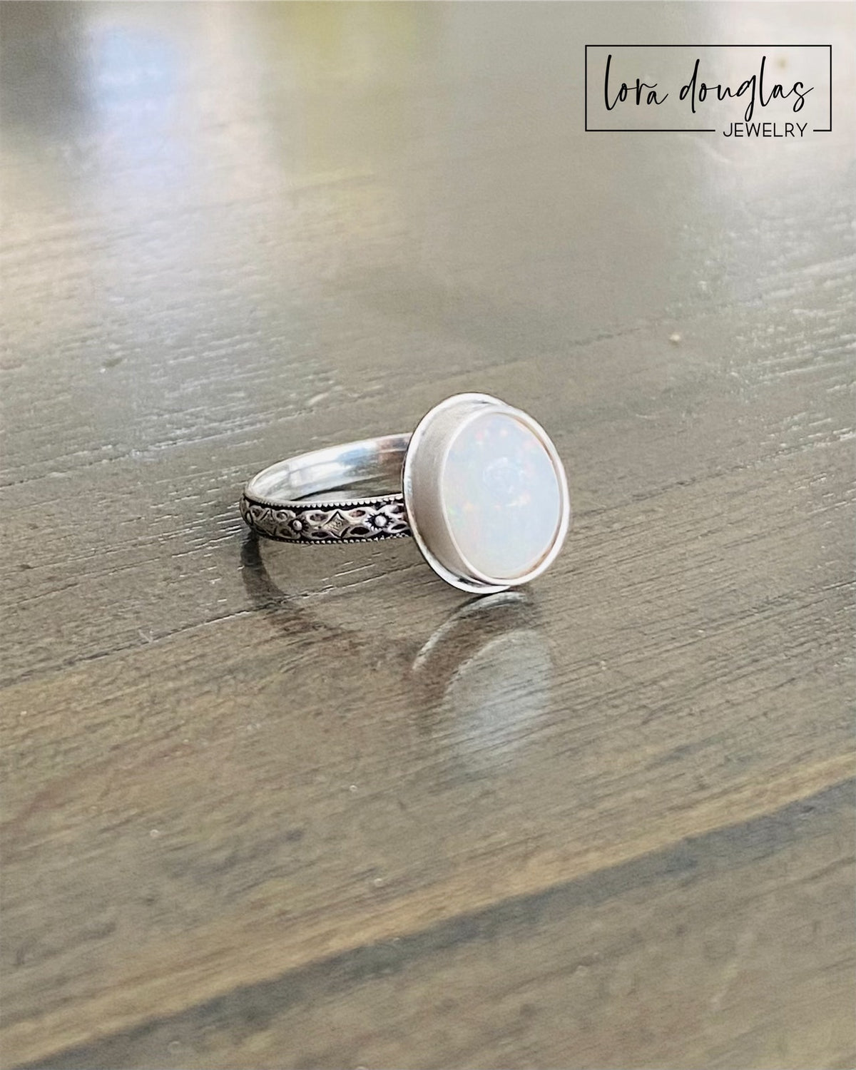 Close view of a hand cut opal cabochon measuring 10mm x 12mm in a handcrafted .925 sterling silver bezel, highlighting the oval gemstone and detailed setting of this finished size 7.75 ring.
