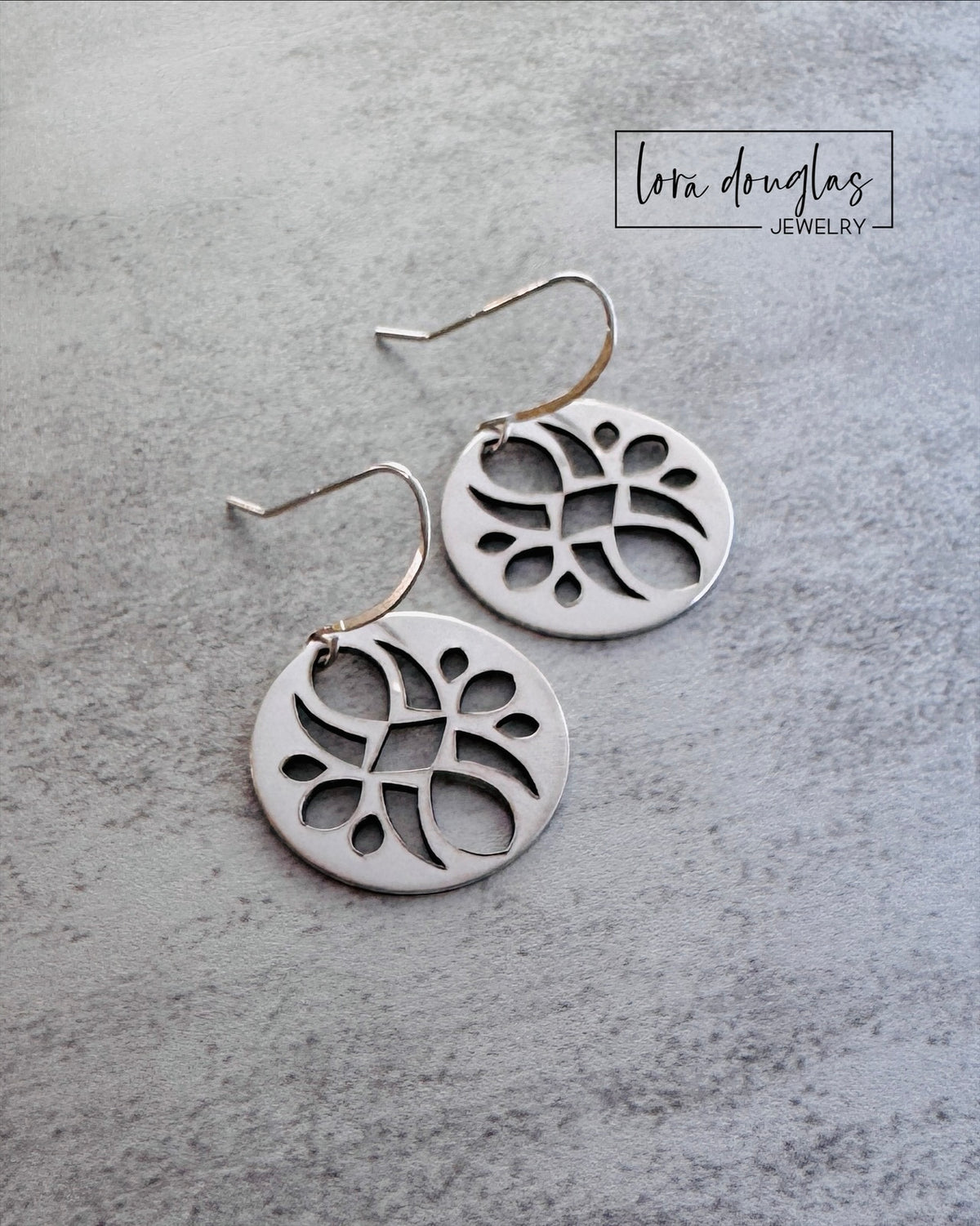 Close view of handmade 925 sterling silver disc earrings showing the detailed cutout pattern within each round 7/8 inch dangle, highlighting the open design and handcrafted character of these artisan earrings.
