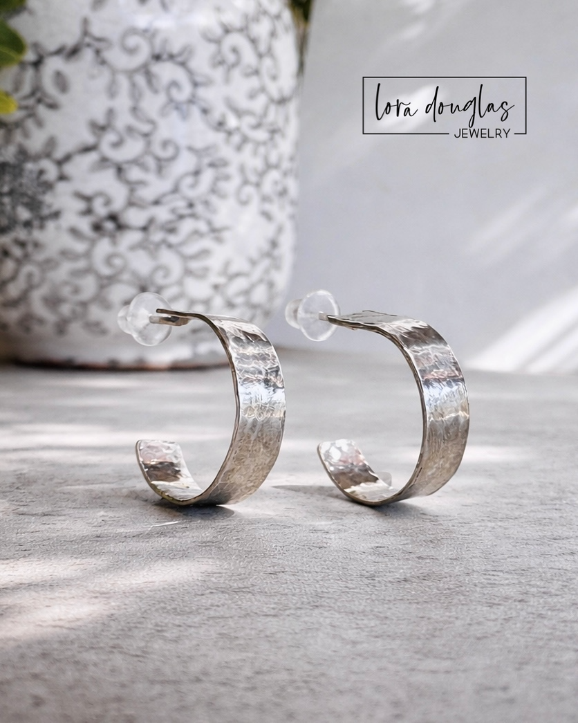 Close view of small sterling silver hoop earrings showing the hammered finish across the silver surface, with a lightweight 0.5 inch design for shoppers seeking classic everyday hoops with subtle texture.
