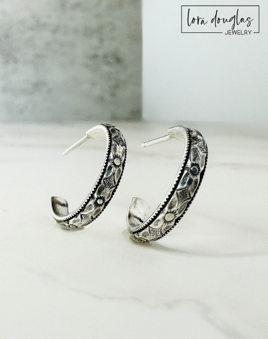 Close view of small sterling silver hoop earrings showing their classic curved shape and petite proportions, with 925 silver posts and clear backs included for a simple and versatile earring design.
