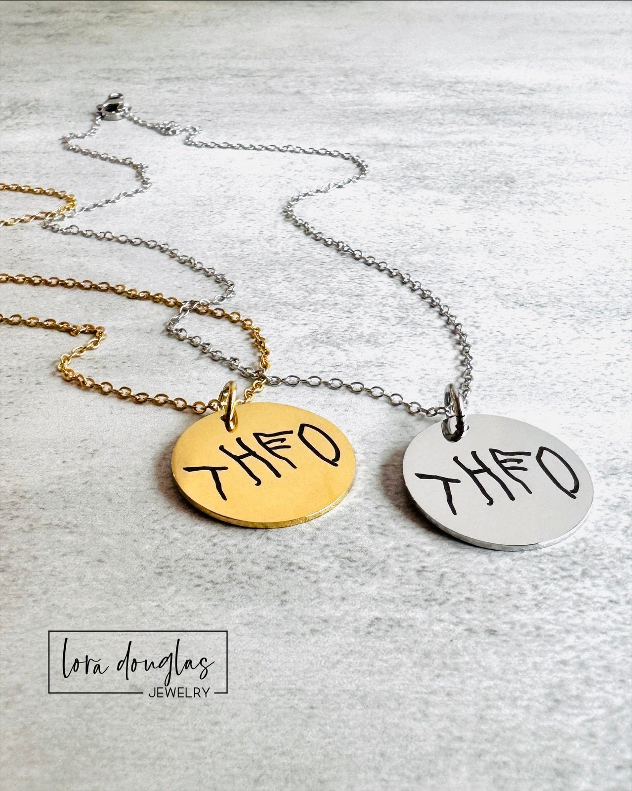 Comparison of sterling silver and stainless steel handwriting jewelry options showing custom engraved round pendants. Personalized keepsake jewelry available as a charm, necklace, or bracelet with permanent engraving.