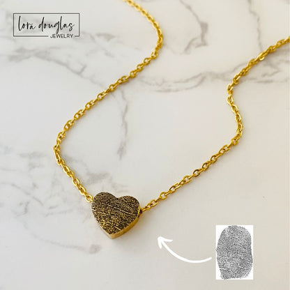 A gold stainless steel necklace with a heart-shaped pendant engraved with a fingerprint