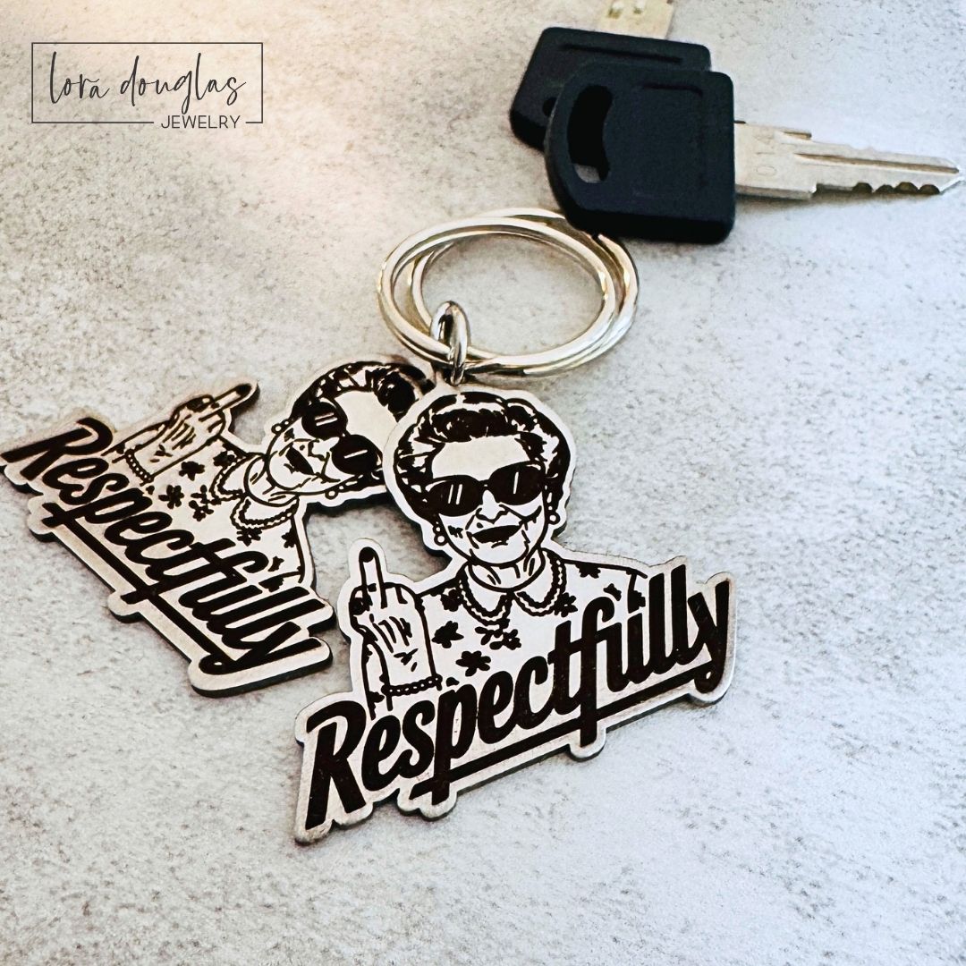 Front and back view of the Respectfully middle finger keychain showing the detailed permanent front engraving and optional personalized text engraved on the brushed stainless steel back.