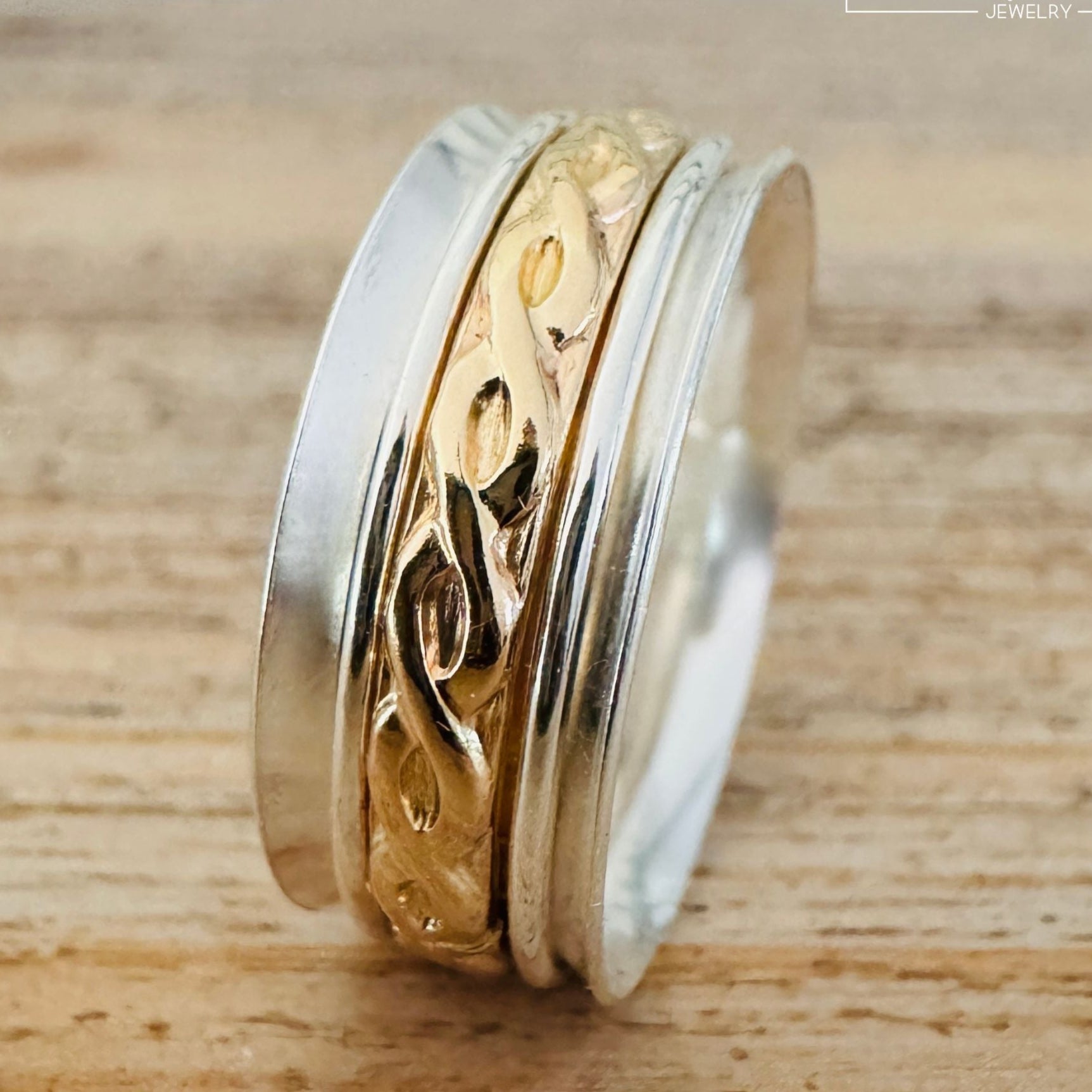 Gold-filled and sterling silver spinner ring turned to display the intricate vine pattern from a side angle, artisan-made by Lora Douglas Jewelry.