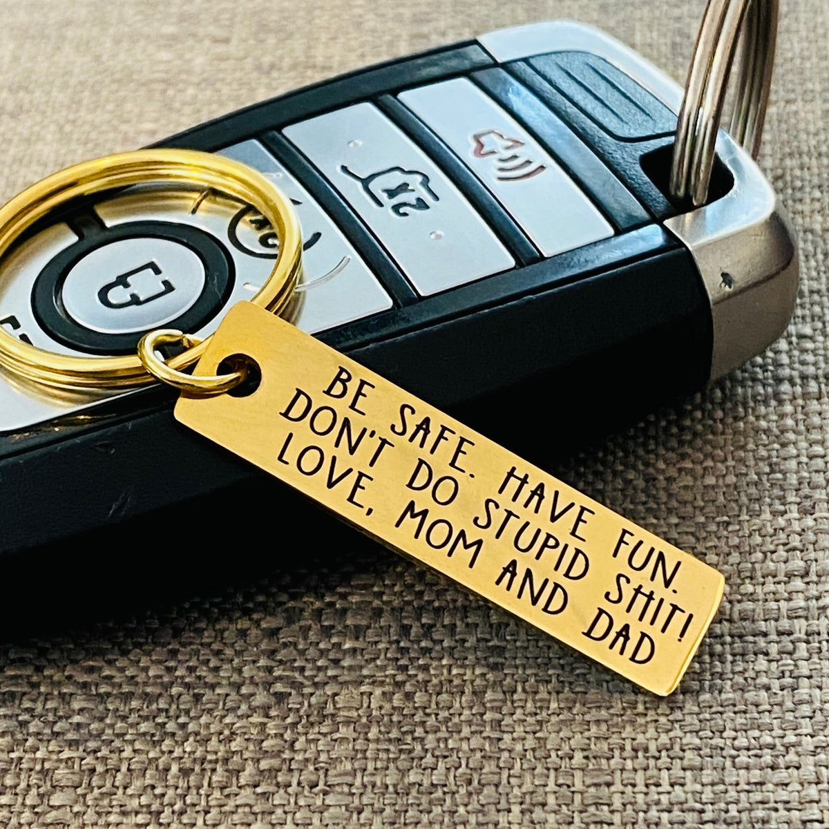 Gold stainless steel new car keychain with permanent personalized engraving and the message Don't Do Stupid Shit, a funny gift idea for a teen getting their first car, new driver, daughter, son or best friend.
