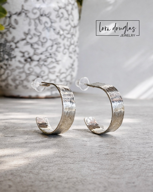 Hammered sterling silver hoops featuring a compact 0.5 inch silhouette and textured silver surface, creating lightweight earrings for comfortable everyday wear with casual, professional or dressier outfits.
