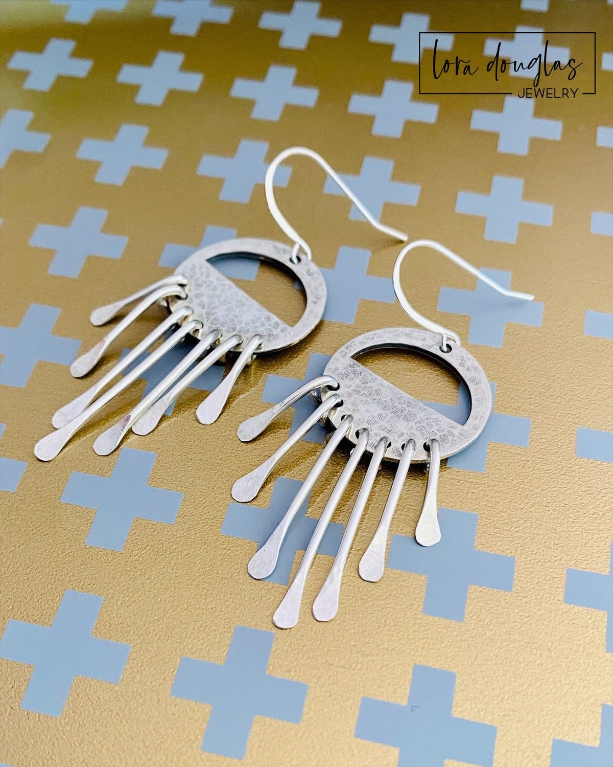 Handcrafted sterling silver dangle earrings inspired by the shape and movement of wind chimes, featuring long silver fringe and sterling silver ear wires in a lightweight approximately 2.5 inch statement design.
