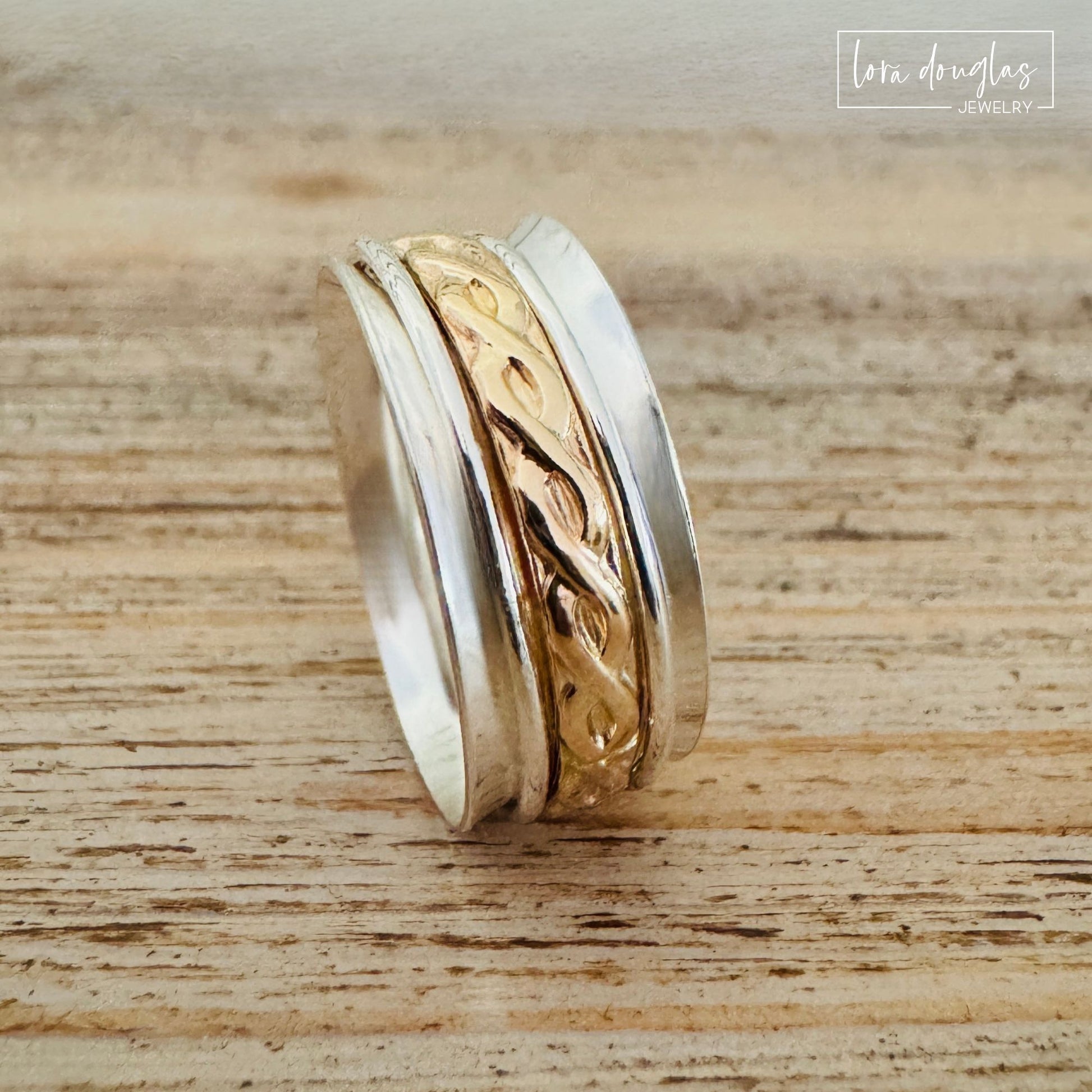 Handcrafted sterling silver spinner ring with a detailed gold-filled center band featuring a twisted vine pattern, made by Lora Douglas Jewelry.