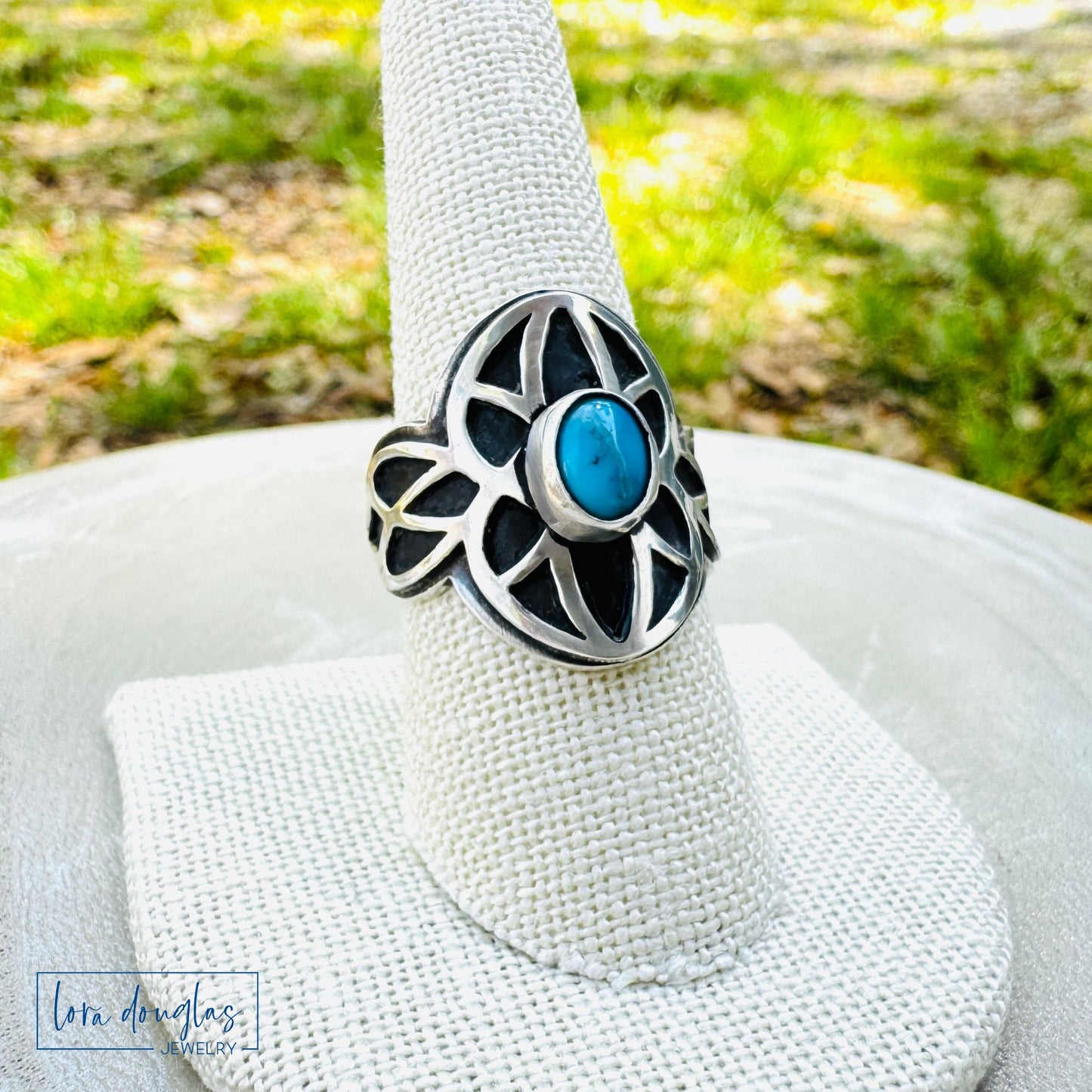 Sterling silver ring with a blue turquoise stone on a white cushion outdoors from lora douglas jewelry