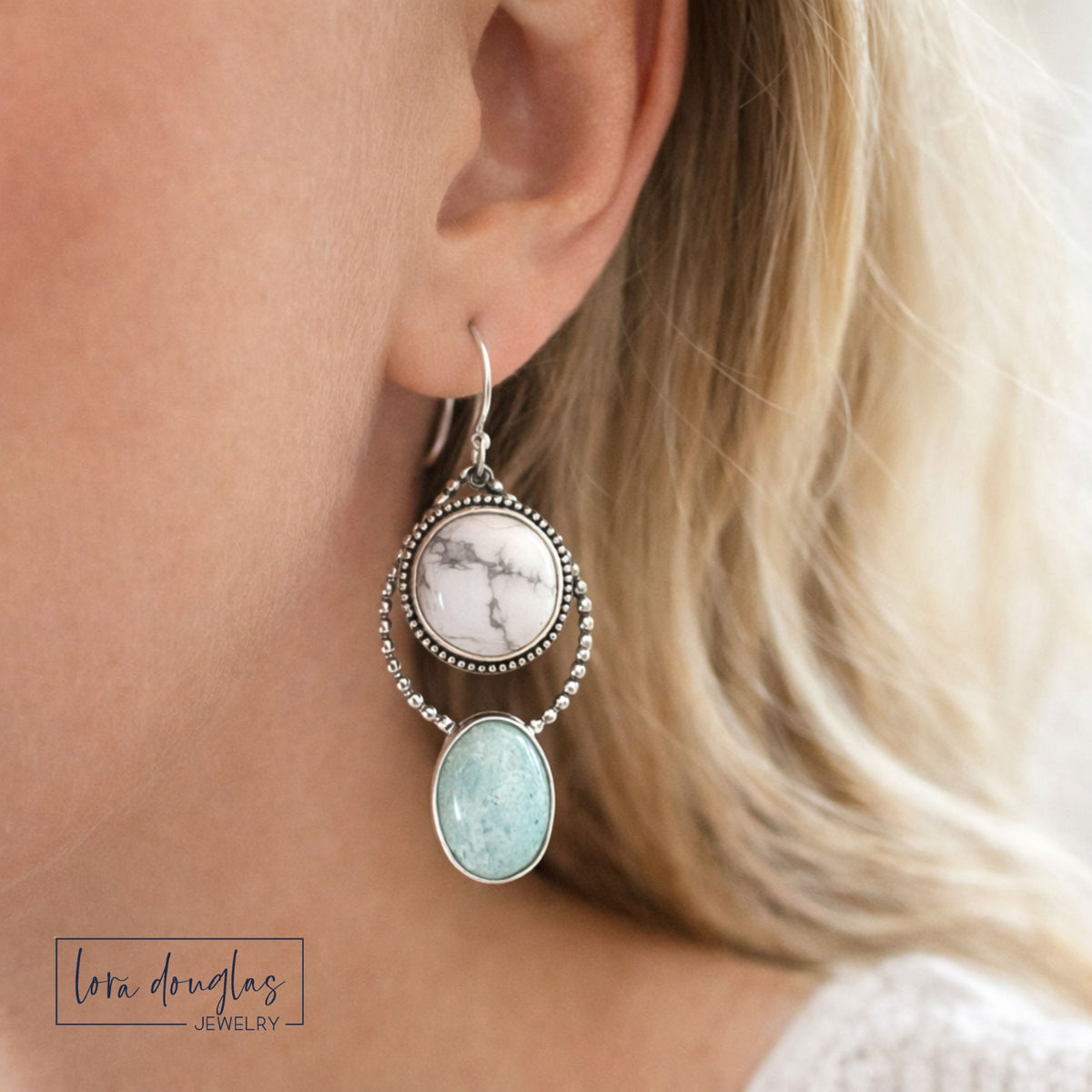 Howlite and amazonite sterling silver earrings worn on the ear, featuring white marbled and soft green oval natural stones in a long dangle design for shoppers looking for distinctive gemstone jewelry.
