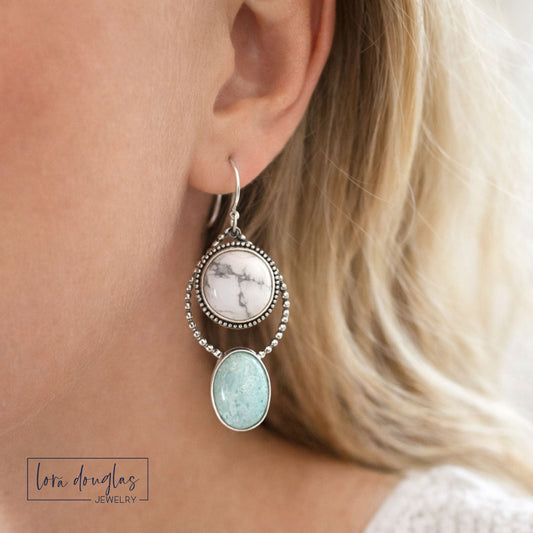 Howlite and amazonite sterling silver earrings worn on the ear, featuring white marbled and soft green oval natural stones in a long dangle design for shoppers looking for distinctive gemstone jewelry.
