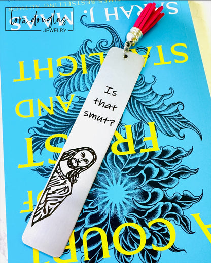 Is that smut bookmark. A stainless steel bookmark with  a leather tassel, featuring a laser engraving of a Jesus character with the text Is that Smut?