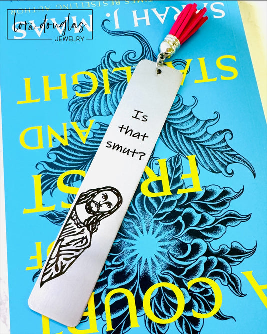 Is that smut bookmark. A stainless steel bookmark with  a leather tassel, featuring a laser engraving of a Jesus character with the text Is that Smut?