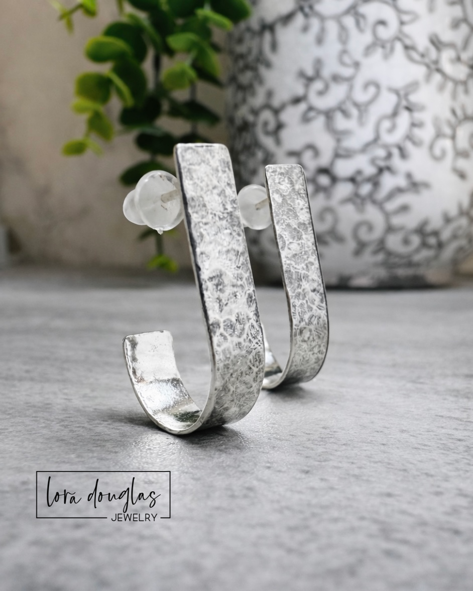 Lightweight silver hoop earrings crafted from sterling silver with matching sterling silver posts, featuring a textured 22mm x 5mm design that adds dimension while maintaining a clean everyday look.
