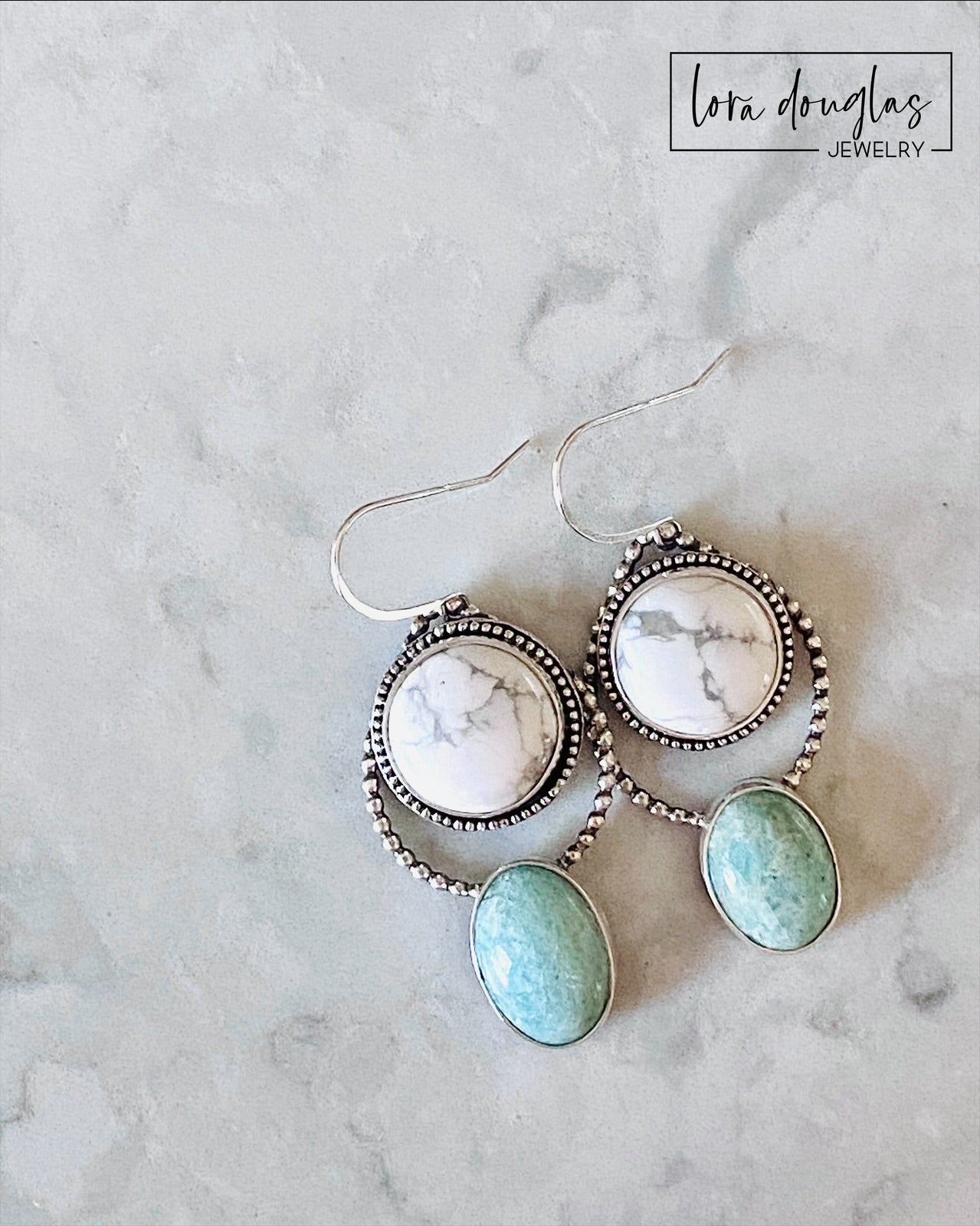 Long gemstone dangle earrings featuring natural white howlite and green amazonite stones in sterling silver, shown on the ear for scale and styled as distinctive artisan jewelry for everyday or dressier outfits.
