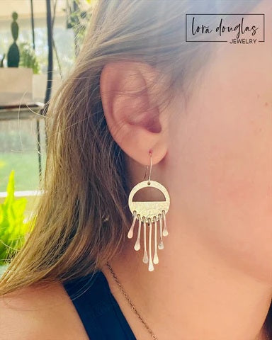 Long sterling silver earrings featuring a wind chime inspired arrangement of dangling silver elements, handcrafted as lightweight statement earrings for shoppers who enjoy artisan silver jewelry with movement and texture.

