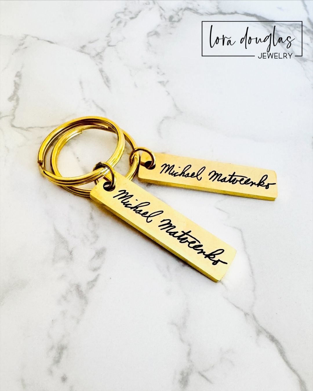 Gold keychain with engraved handwritten name on a marble surface