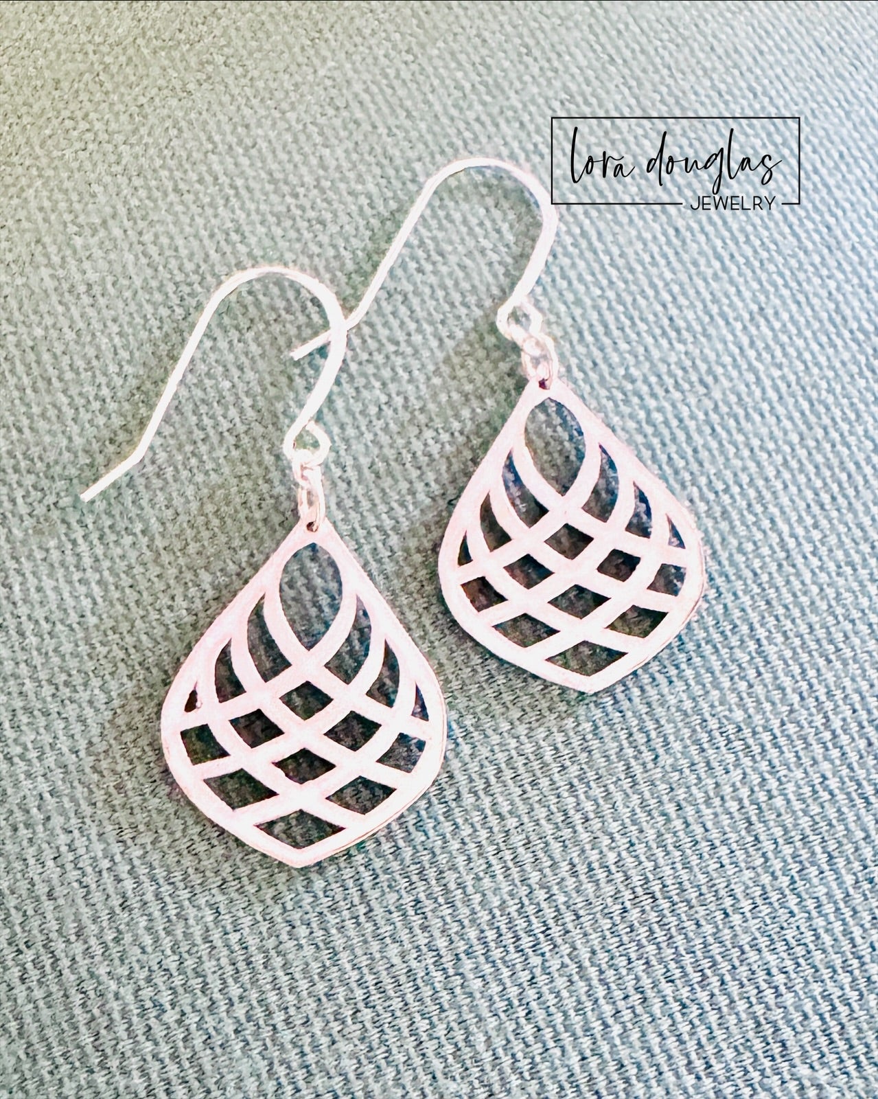 Pair of lightweight silver dangle earrings laying flat, showcasing their symmetrical teardrop shape and fine detailing
