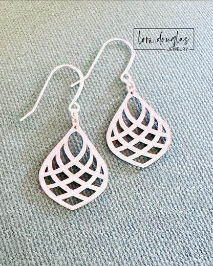 Pair of lightweight silver dangle earrings laying flat, showcasing their symmetrical teardrop shape and fine detailing