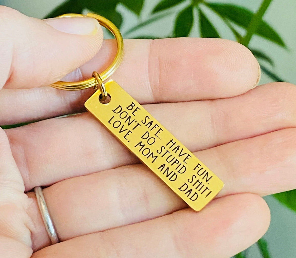 Personalized new driver keychain made from gold stainless steel with a mirror finish and custom name engraving, featuring the funny reminder Be Safe, Have Fun, Don't Do Stupid Shit for a teen driver gift.
