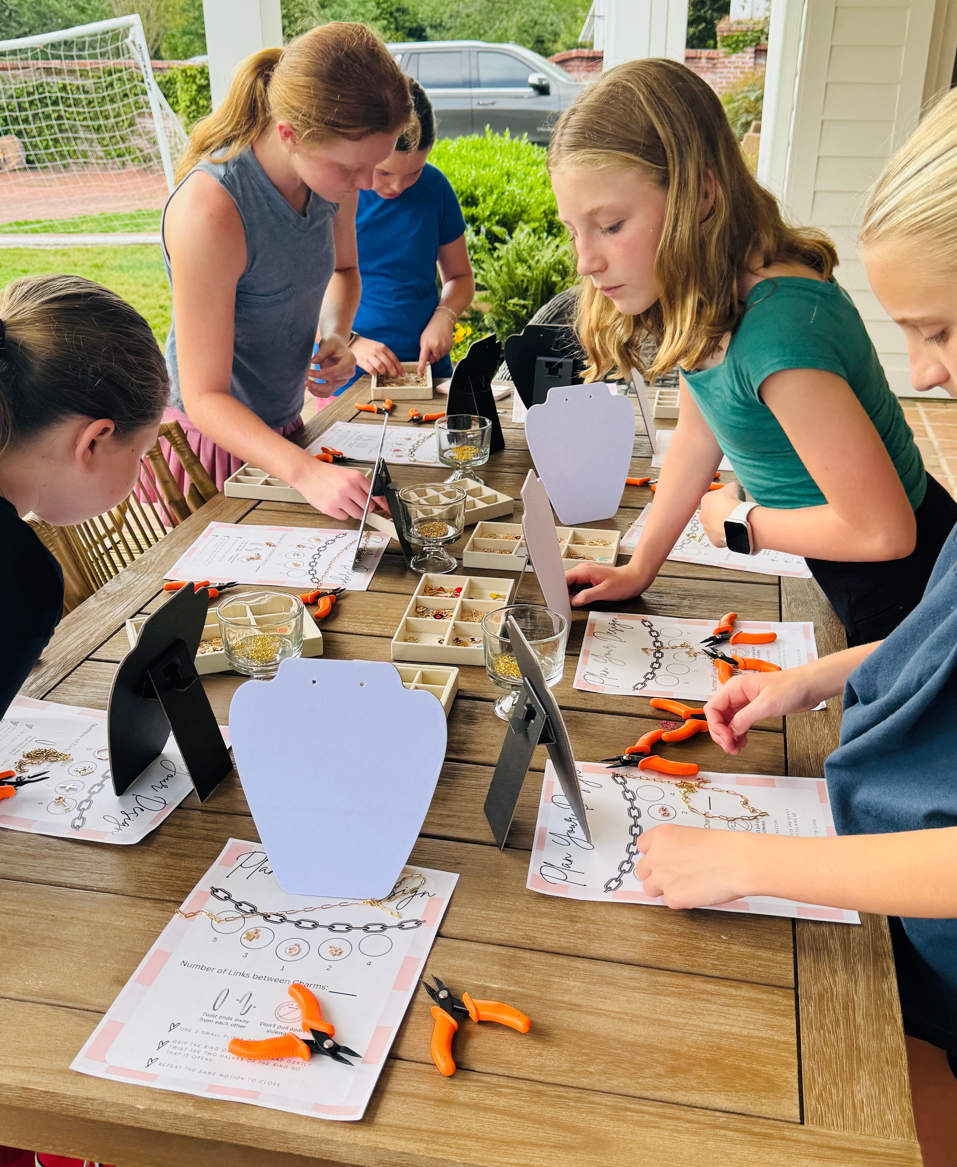 Children working on craft projects at a table outdoors.