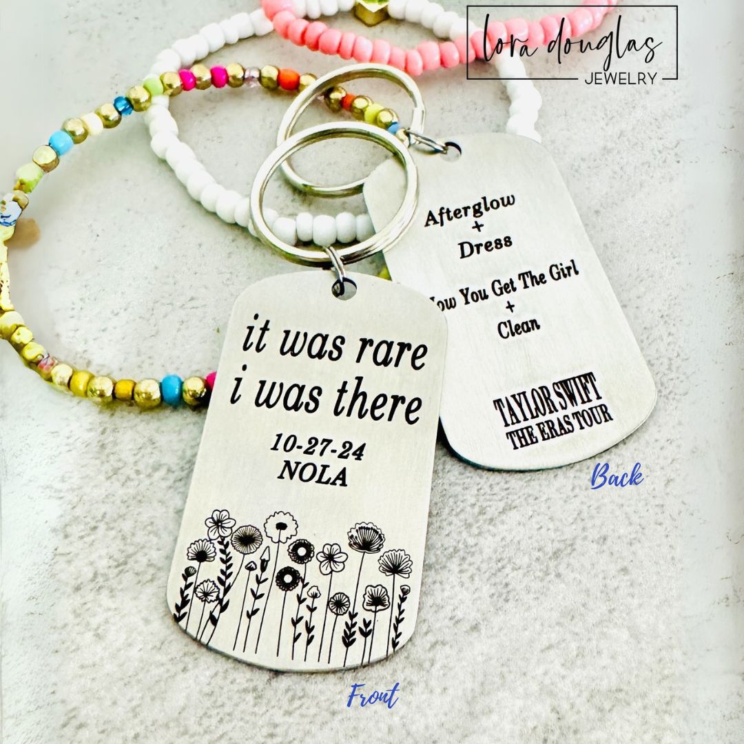 Two silver stainless steel keychains with brushed metal finish. One keychain has text 'It was rare I was there' and the other has the text 'AFTERGLOW THE GIRL I WAS THERE' along with a date '10.