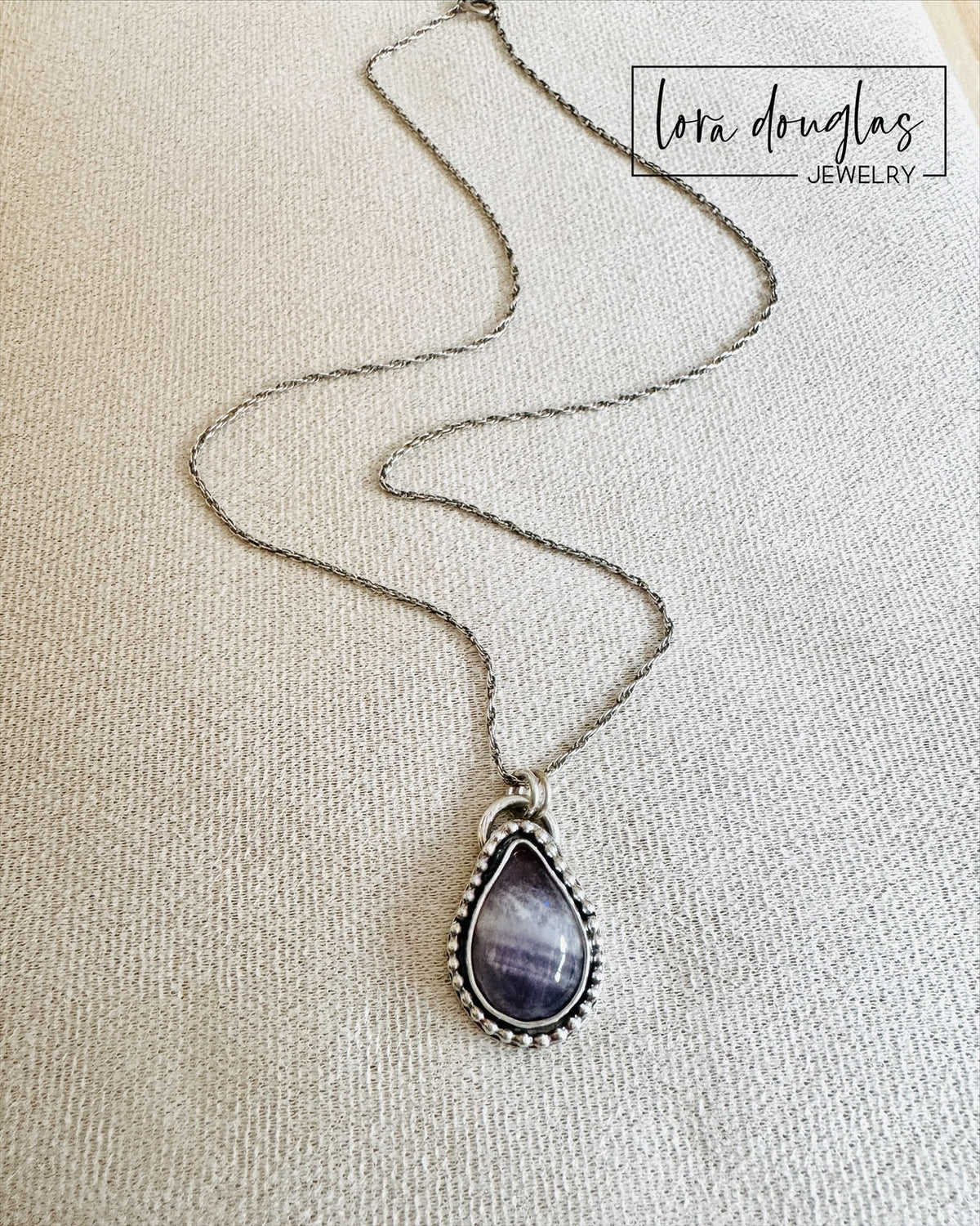 Purple gemstone necklace featuring natural banded amethyst in a teardrop pendant with an 18 inch sterling silver chain, a distinctive natural stone jewelry choice for amethyst collectors and purple jewelry lovers.
