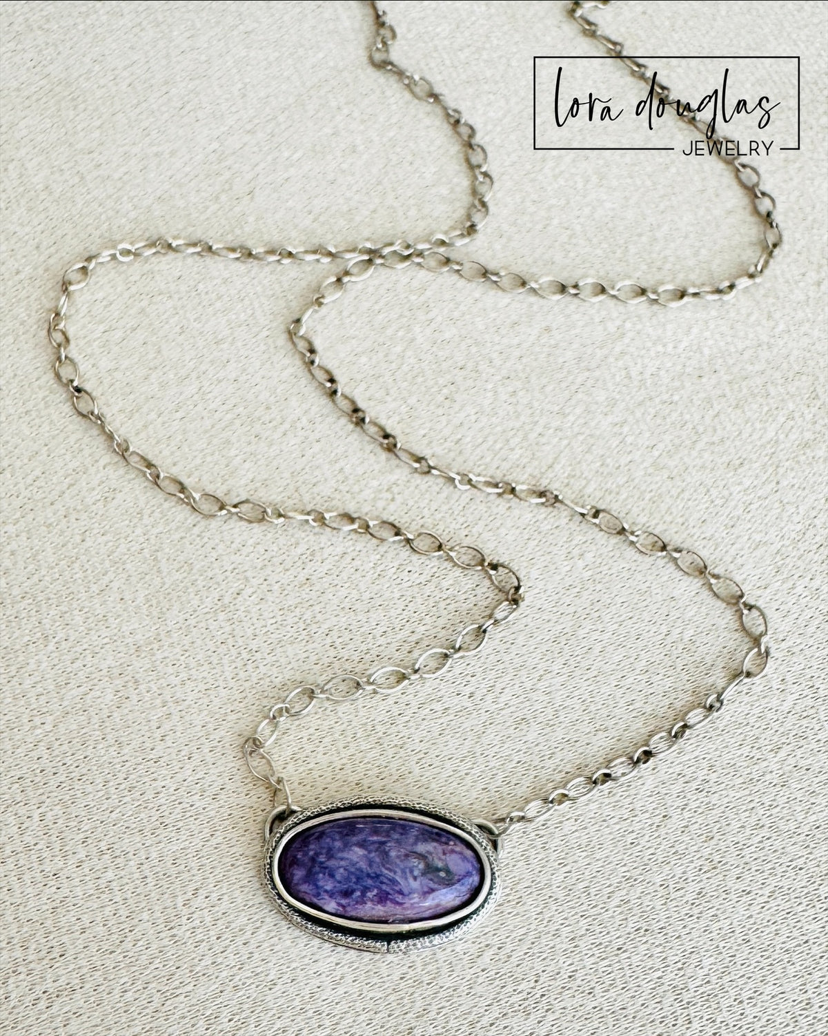 Purple gemstone necklace featuring natural charoite in an oval sterling silver pendant with an approximately 20 inch chain, a distinctive natural stone jewelry choice for charoite collectors and purple jewelry lovers.

