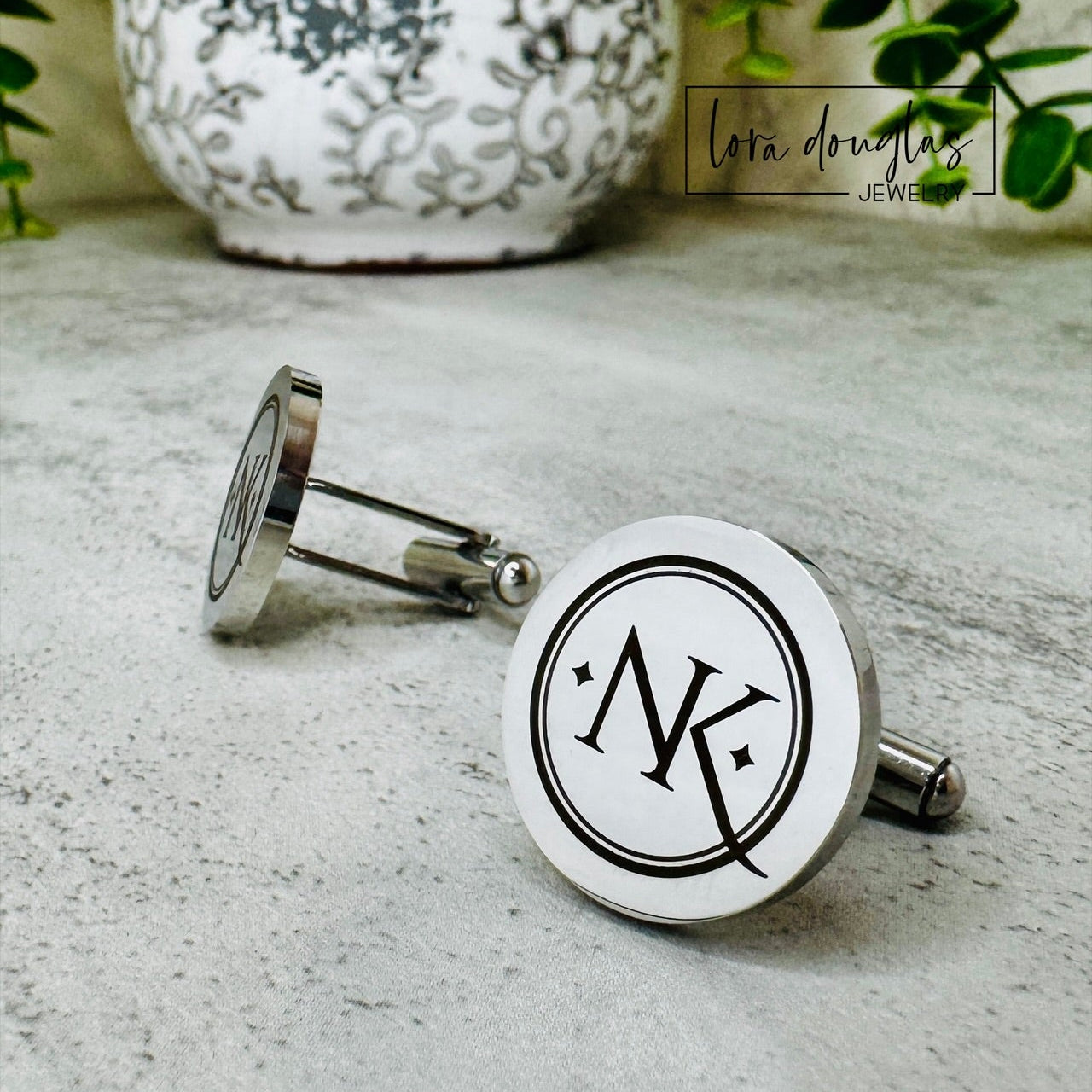 Silver Cufflinks engraved with a logo on a textured surface, with 'lora Douglas' branding.