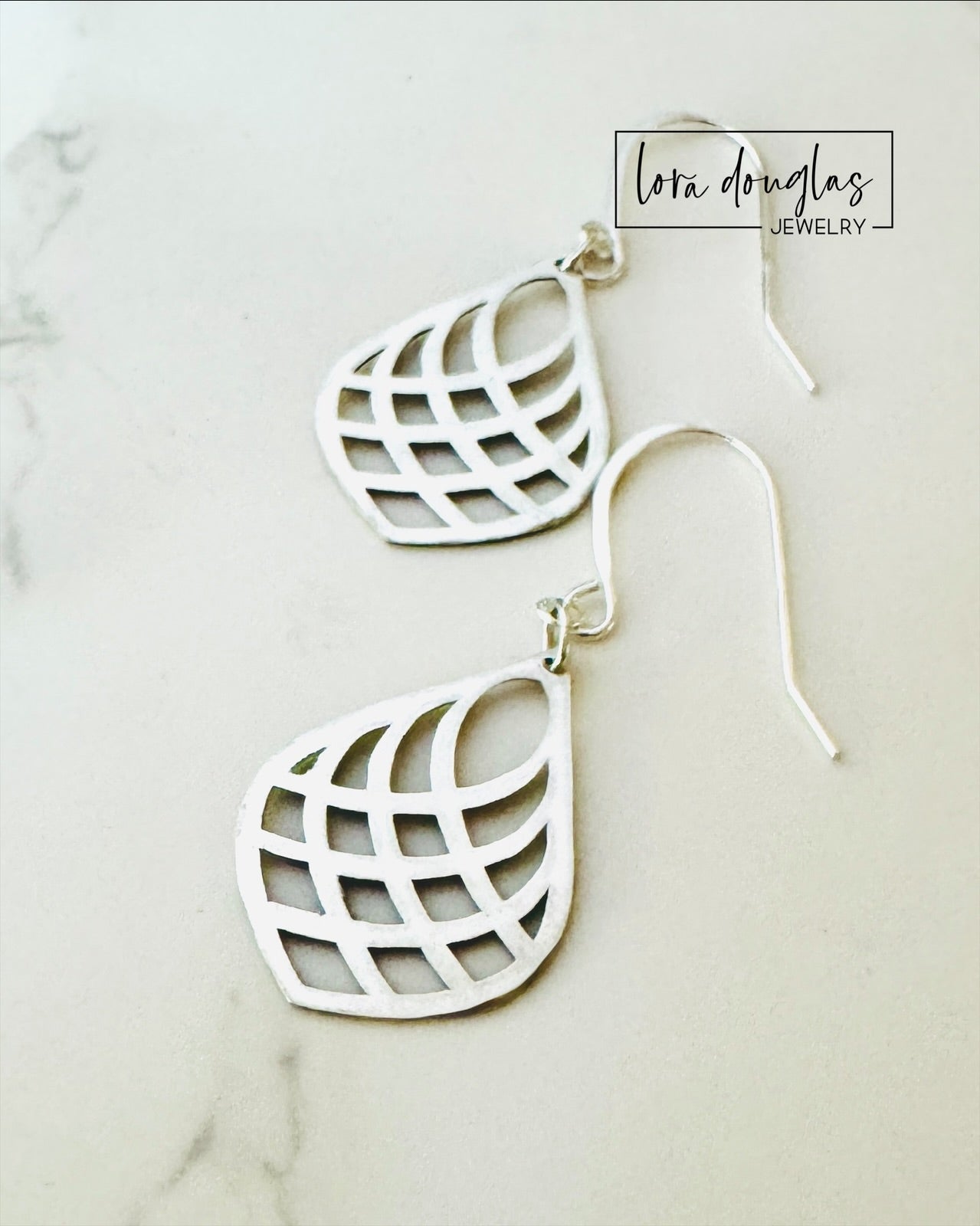 Silver lattice-style earrings on a light background