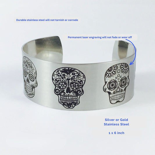 Silver stainless steel sugar skull bracelet with detailed engraved skull artwork wrapping around the wide cuff, featuring a matte finish and 1 inch width for women who love skull jewelry and alternative accessories.
