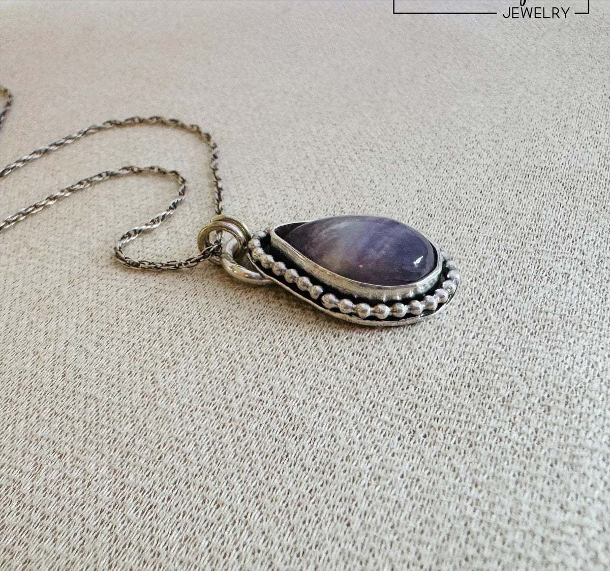 Sterling silver amethyst pendant necklace showcasing a natural banded purple stone in a 17mm x 27mm teardrop shape, a distinctive gemstone jewelry design for shoppers who love natural stones and artisan style jewelry.
