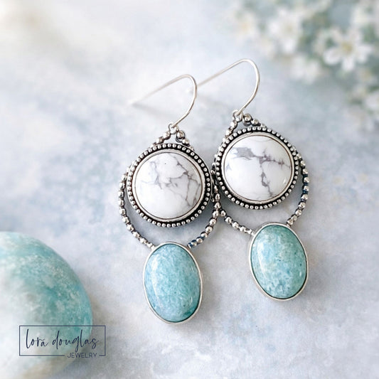 Sterling silver dangle earrings featuring white howlite and soft green amazonite natural stones, shown worn on the ear to display the approximately 2 inch length and eye catching two stone design.
