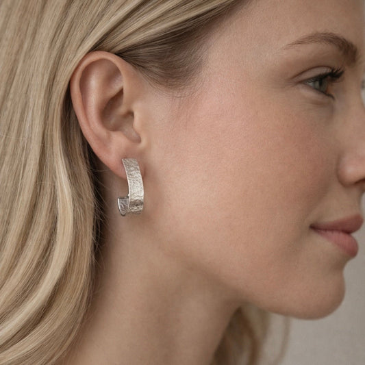 Sterling silver hoop earrings featuring a subtle textured surface that catches the light, shown in a versatile 22mm x 5mm size for shoppers looking for lightweight everyday silver jewelry.
