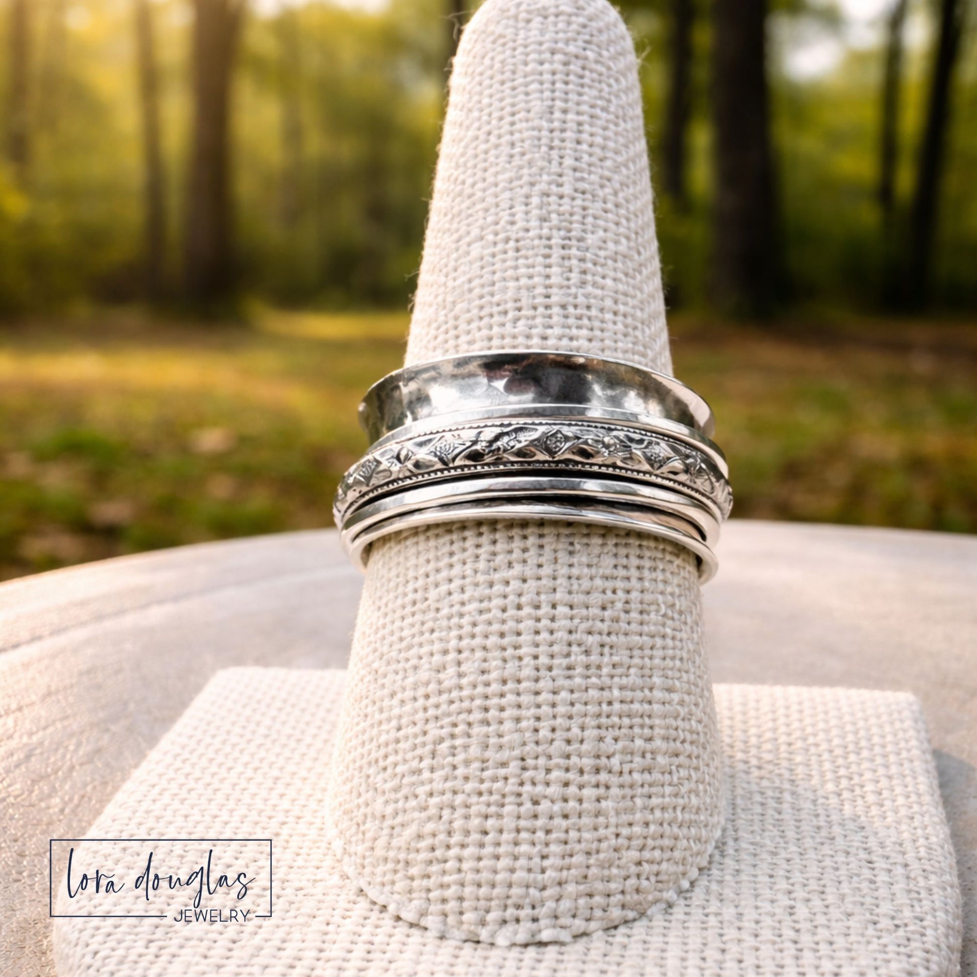 Sterling silver spinner ring with detailed floral band, close up outdoor lifestyle image with natural light