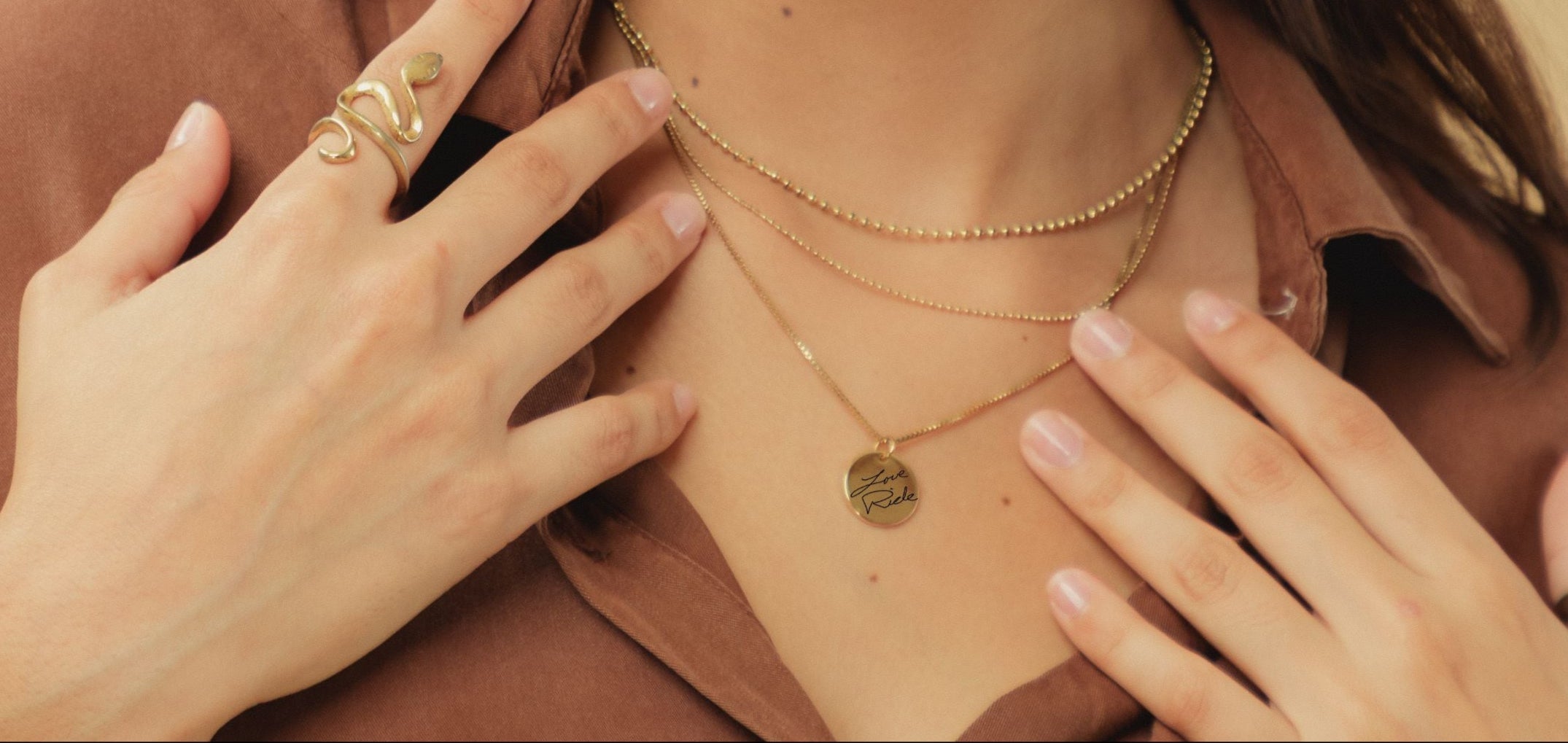 Woman wearing gold necklaces and rings on a beige background