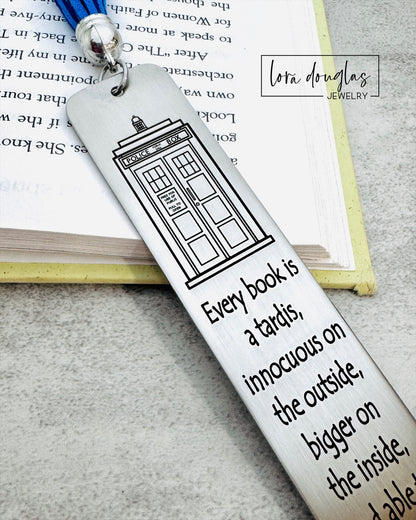 Bookmark with TARDIS design and quote on a book, featuring Lora Douglas Jewelry branding.